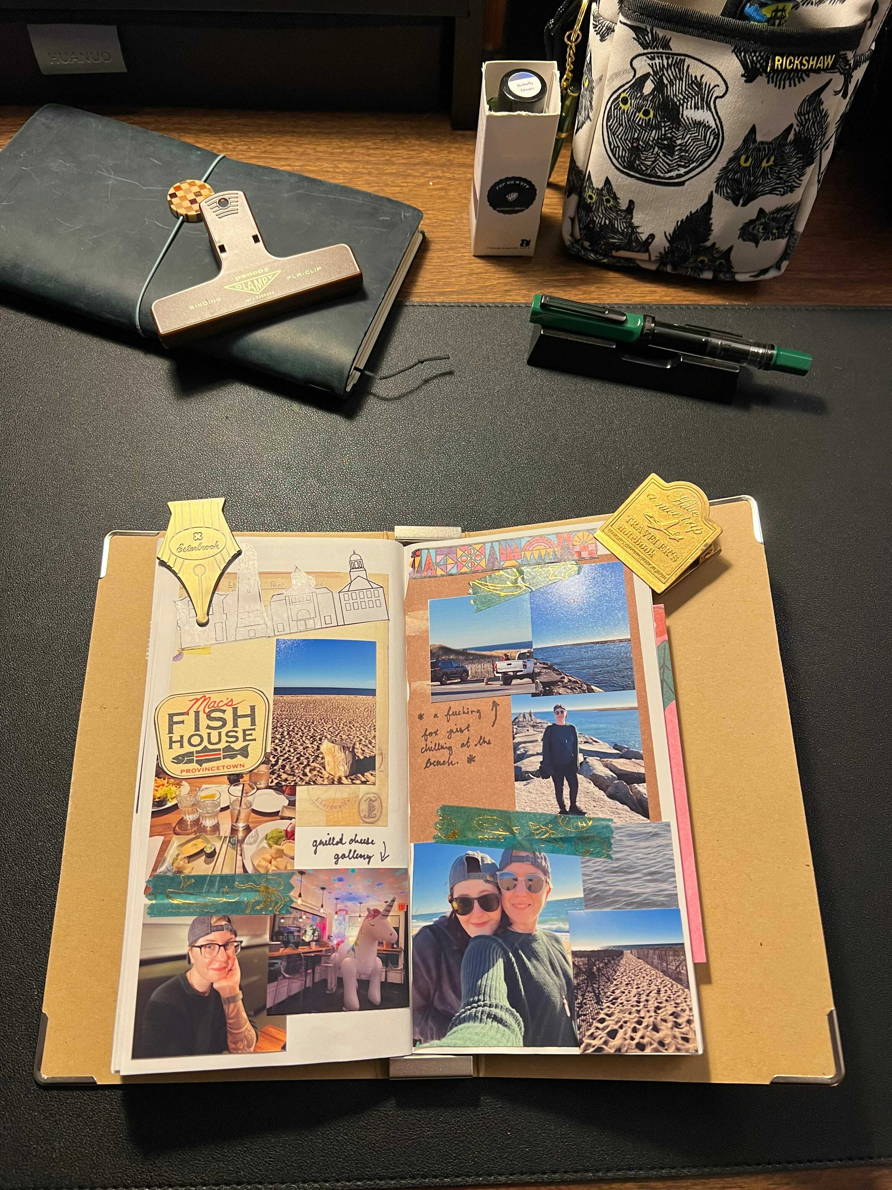 Auto-generated description: A scrapbook page is open on a desk, featuring photos of a beach outing with various travel-themed stickers and notes, surrounded by stationery items and a camera bag.