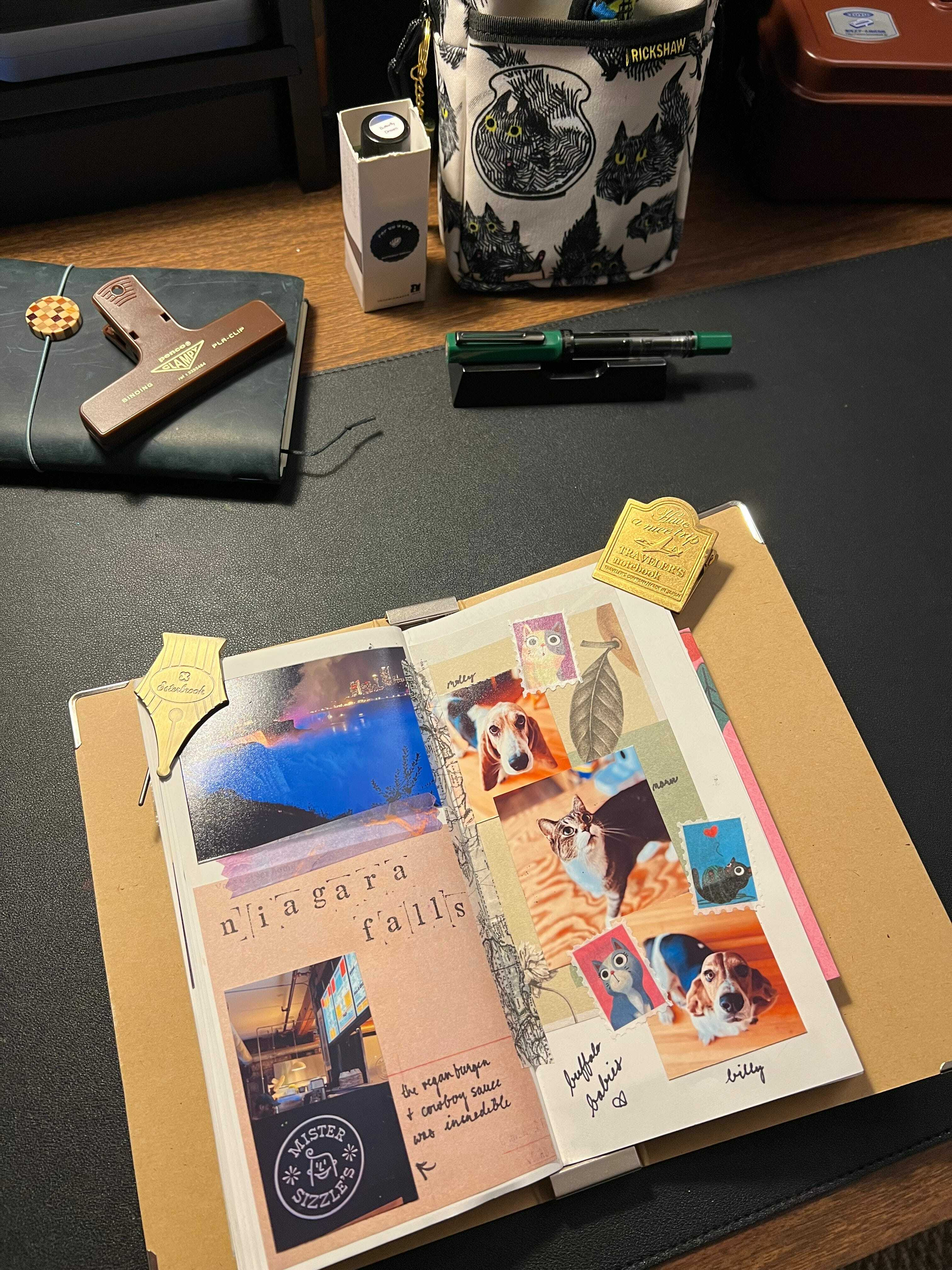 Auto-generated description: A decorated journal page with photos, stickers, and notes about Niagara Falls is surrounded by various stationery items on a desk.